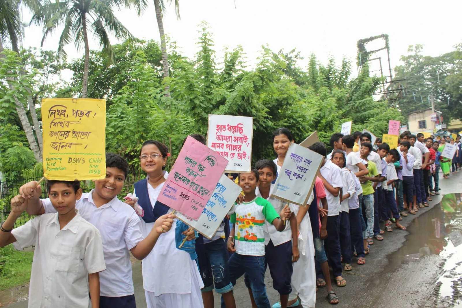 A group of children participating in a DSWS event, holding signs and smiling.